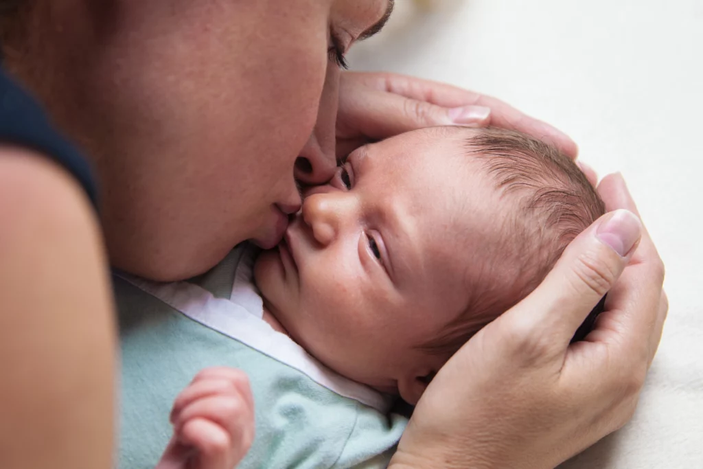 A woman kissing her newborn baby